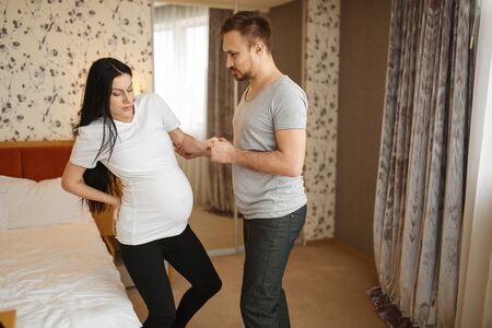Husband helps his pregnant wife with belly at homeの写真素材