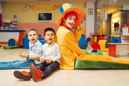 Funny clown play with boys in kindergartenの写真素材