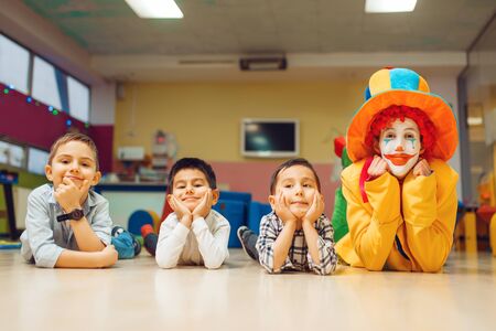 Funny clown and little children lying on the floorの写真素材