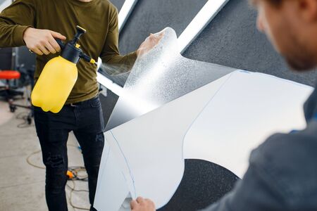 Workers wets car protection film before applyingの写真素材