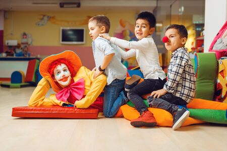 Joyful little boys sitting on funny clownの写真素材