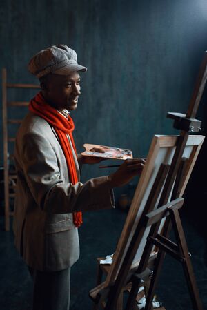 Fashionable painter with palette poses at easelの写真素材