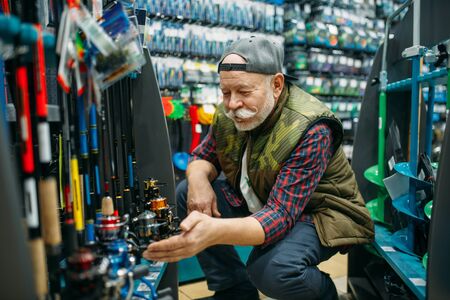 Fisherman choosing reel in fishing shopの写真素材