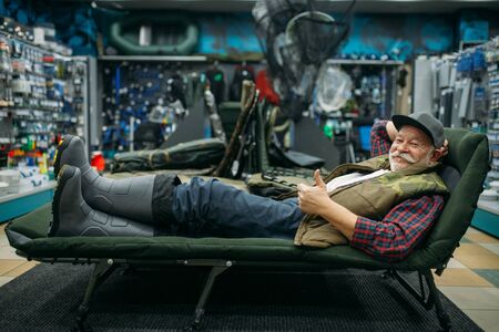 Smiling angler lying in sunbed, fishing shopの写真素材