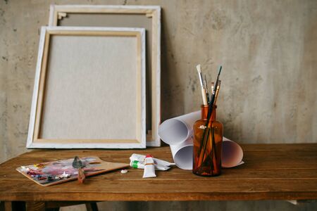 Paints on palette, brush in bottle, canvas, nobody