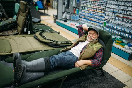 Smiling angler lying in sunbed, fishing shopの写真素材