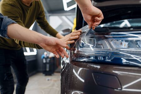 Workers applies car protection film on fenderの写真素材