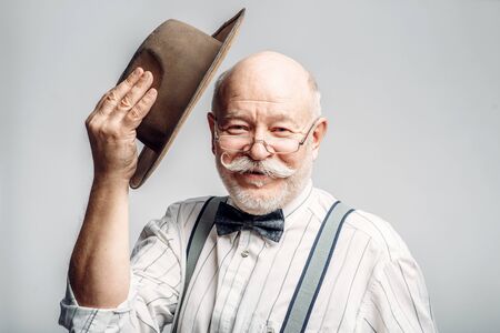 Elderly man in glasses takes off his hat