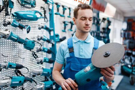 Male worker holds angle grinder in tool storeの写真素材