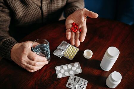 Elderly man hand with pills, age-related diseases