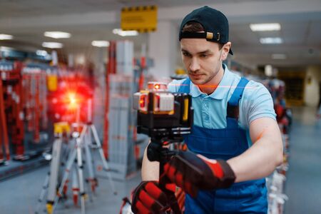 Worker testing laser level on tripod in tool storeの写真素材