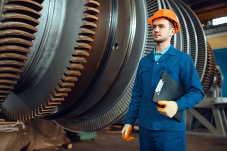 Worker with notebook, large turbine on background