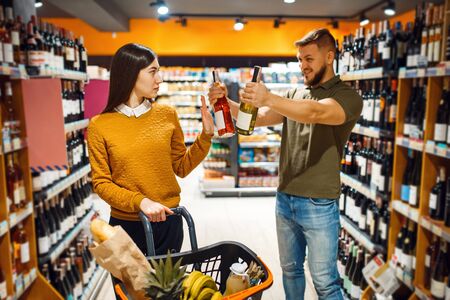 Cheerful couple choosing alcohol in supermarkeの写真素材