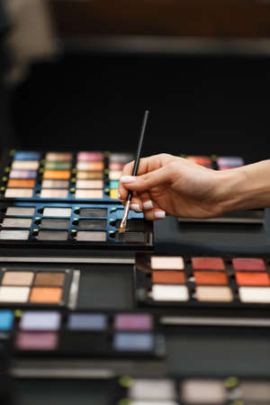 Woman with brush choosing eye shadows in storeの写真素材