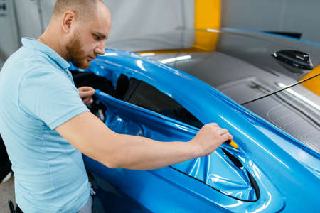 Car wrapping, mechanic cuts vinyl foil or filmの写真素材