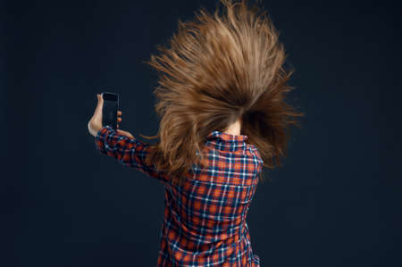 Little girl standing against powerful airflow in studio, back view, developing hairstyle effect. Children and wind, kid isolated on dark background, child emotionの写真素材