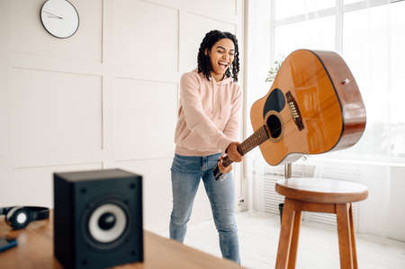 Crazy woman breaks the guitar near audio speaker