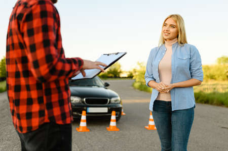 Woman and instructor with checklist on roadの写真素材
