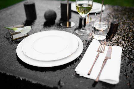 Table setting, glasses, candles and plate on blackの写真素材