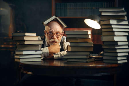 Cute elderly writer at the stack of books