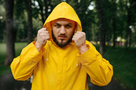 Man in raincoat puts on a hood in rainy dayの写真素材