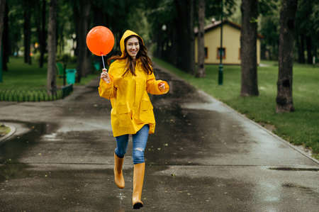 Happy woman runs with balloon in rainy dayの写真素材