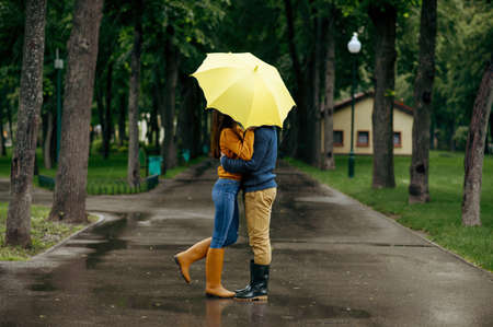 Love couple kissing in park, summer rainy day