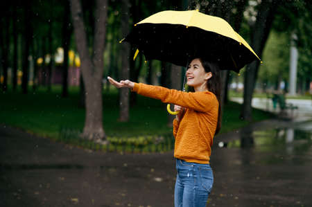 Woman with umbrella enjoys rain in summer parkの写真素材