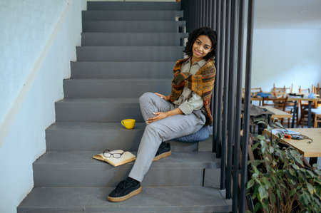 Female student with coffee sitting on on the stepsの写真素材