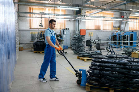 Worker carries bicycle wheels on a cart, factory