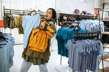 Customer holds clothes on hanger in clothing store