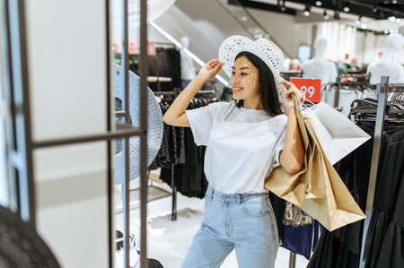 Smiling woman choosing hat in clothing store