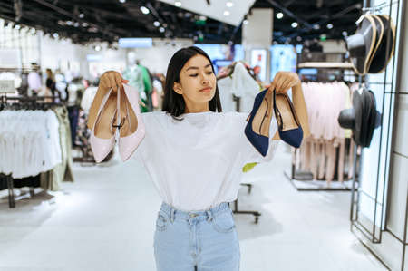 Cute woman choosing shoes in clothing storeの写真素材