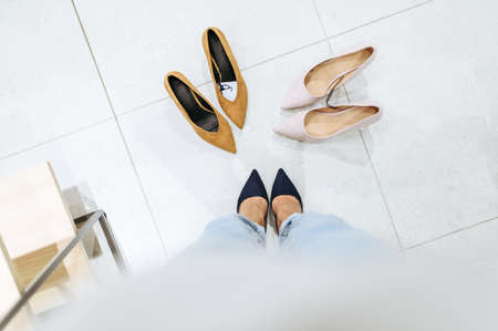 Woman trying on shoes in store, view on feets