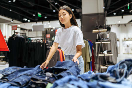 Cheerful woman choosing jeans in clothing storeの写真素材