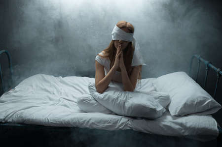 Blindfolded crazy woman in bed, psychedelicの写真素材