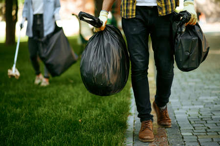 Man holds plastic trash bags in park, volunteeringの写真素材