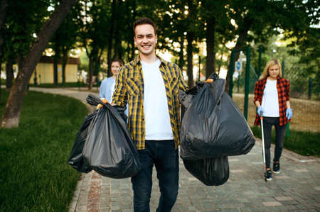 Volunteers holds full plastic trash bags in park