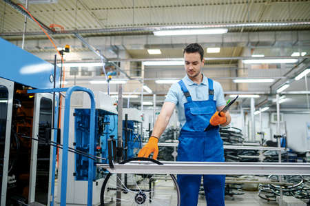 Worker at the assemly line checks bicycle wheels