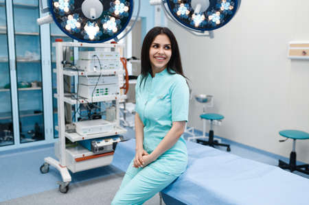 Smiling female surgeon poses at operating tableの写真素材