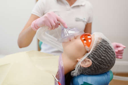 Female dentist puts mask on patient faceの写真素材