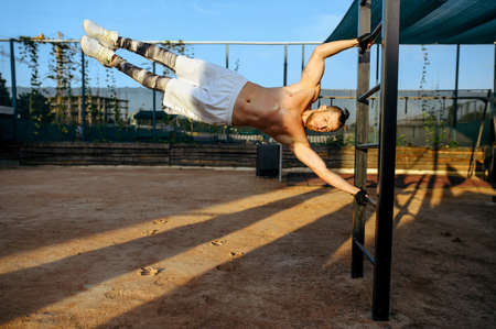 Man hanging horizontally on a bar, street workout