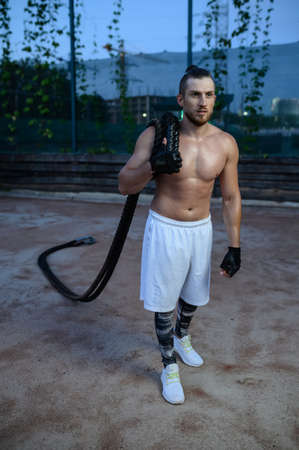 Man poses with crossfit ropes, street workout