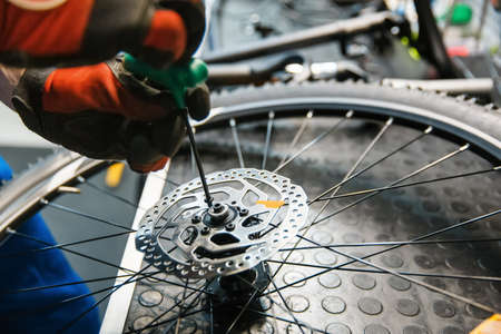 Bicycle assembly in workshop, man installs brakeの写真素材