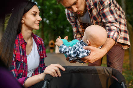 Caring parents with baby walking in summer park