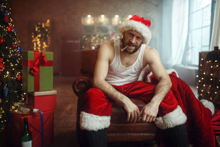 Vile Santa claus in red cap smoking cigar on couchの写真素材
