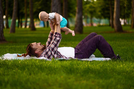 Father and his little baby lying on grass in park