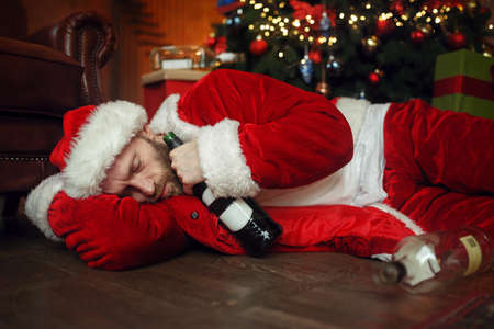 Vile drunk Santa claus sleeps under christmas treeの写真素材