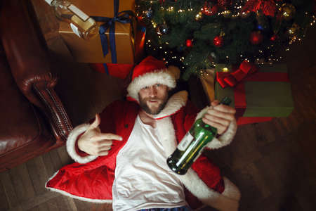 Drunk Santa in underpants under christmas treeの写真素材