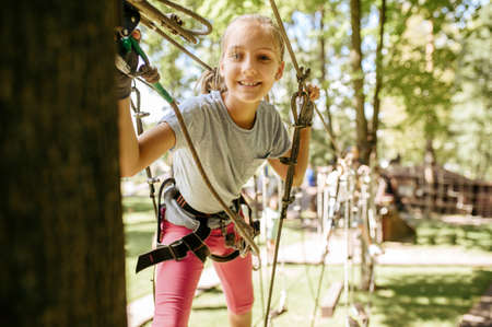 Smiling girl climbs in rope park, playgroundの写真素材